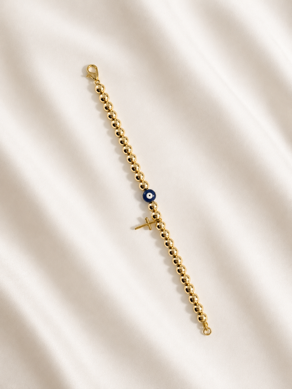 Gold Mati Greek evil eye bracelet with a delicate cross and gold beads, handmade and made to order in Canada, symbolizing faith, strength, and protection.