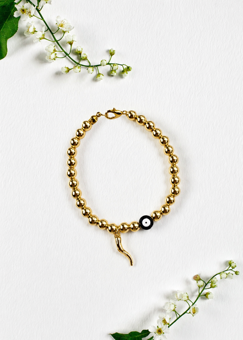 Handmade gold evil eye and Italian horn cornicello bracelet inspired by the traditional Italian symbol of protection from the malocchio, made to order in Canada.