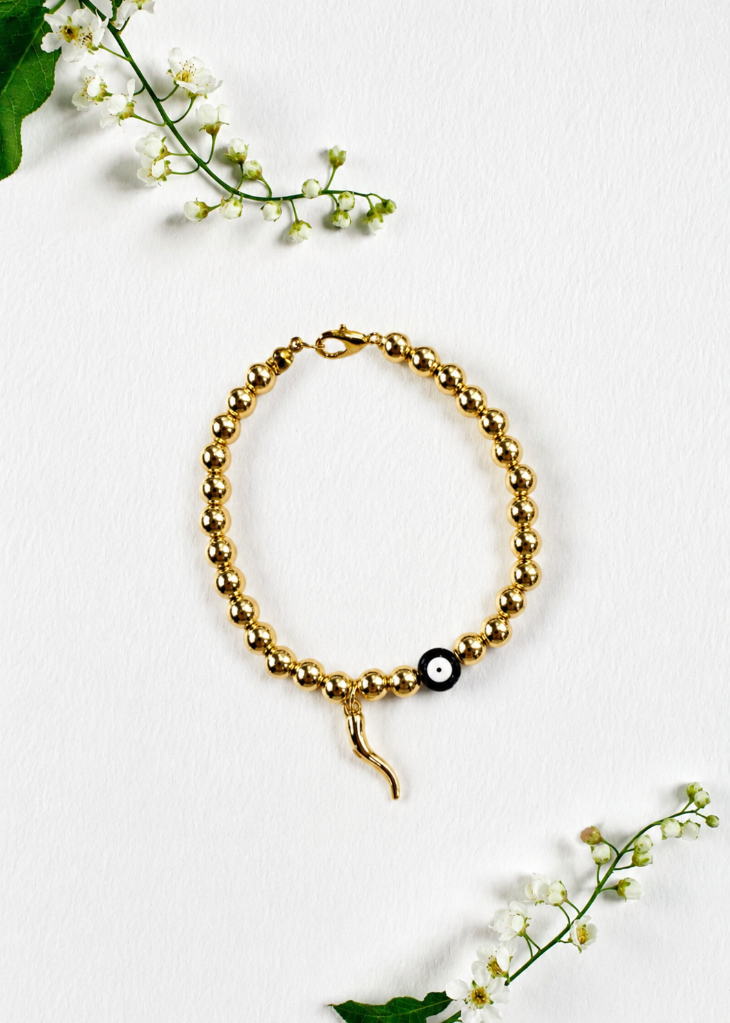 Handmade gold evil eye and Italian horn cornicello bracelet inspired by the traditional Italian symbol of protection from the malocchio, made to order in Canada.