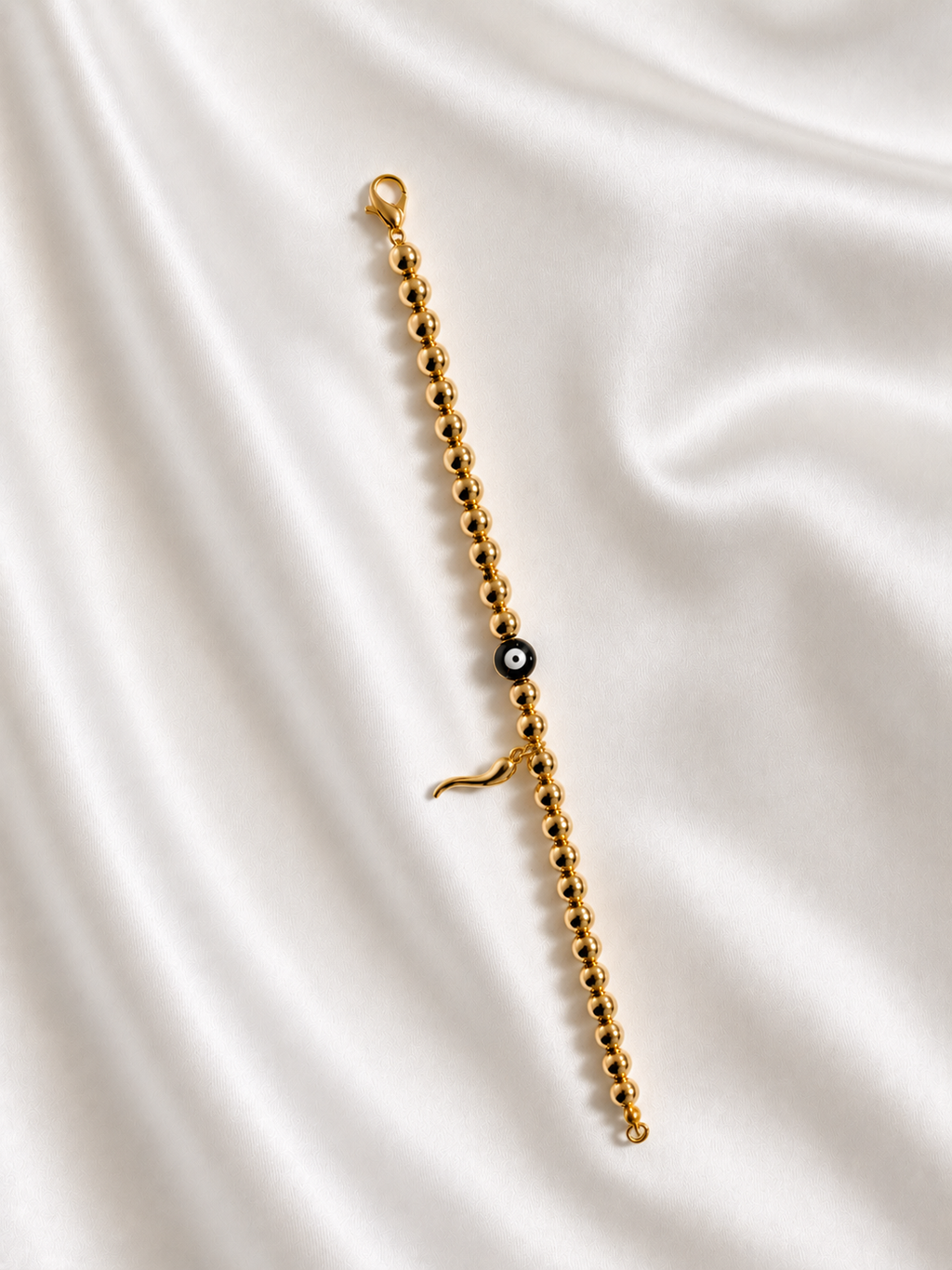 Handmade gold evil eye and Italian horn cornicello bracelet inspired by the traditional Italian symbol of protection from the malocchio, made to order in Canada.